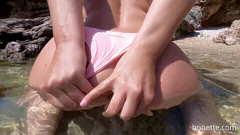 Spina del sedere e doccia dorata sulla spiaggia in bikini