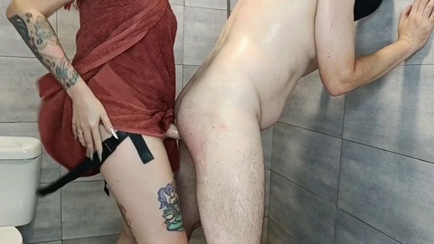 Dominant lady uses strap-on dildo on submissive man's ass post-shower