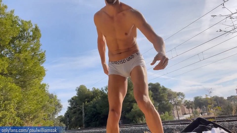 Ripped hunk strips down next to train tracks, showcasing his sizzling physique