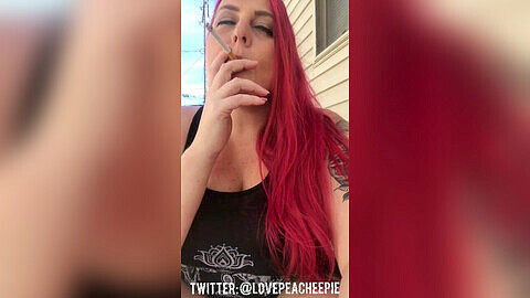 Busty redhead teases with cleavage while casually smoking outside