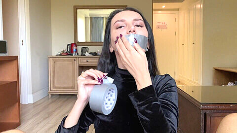 Hermosa chica de cabello negro hace una paja con cinta adhesiva en la boca y recibe eyaculación en su cara bonita